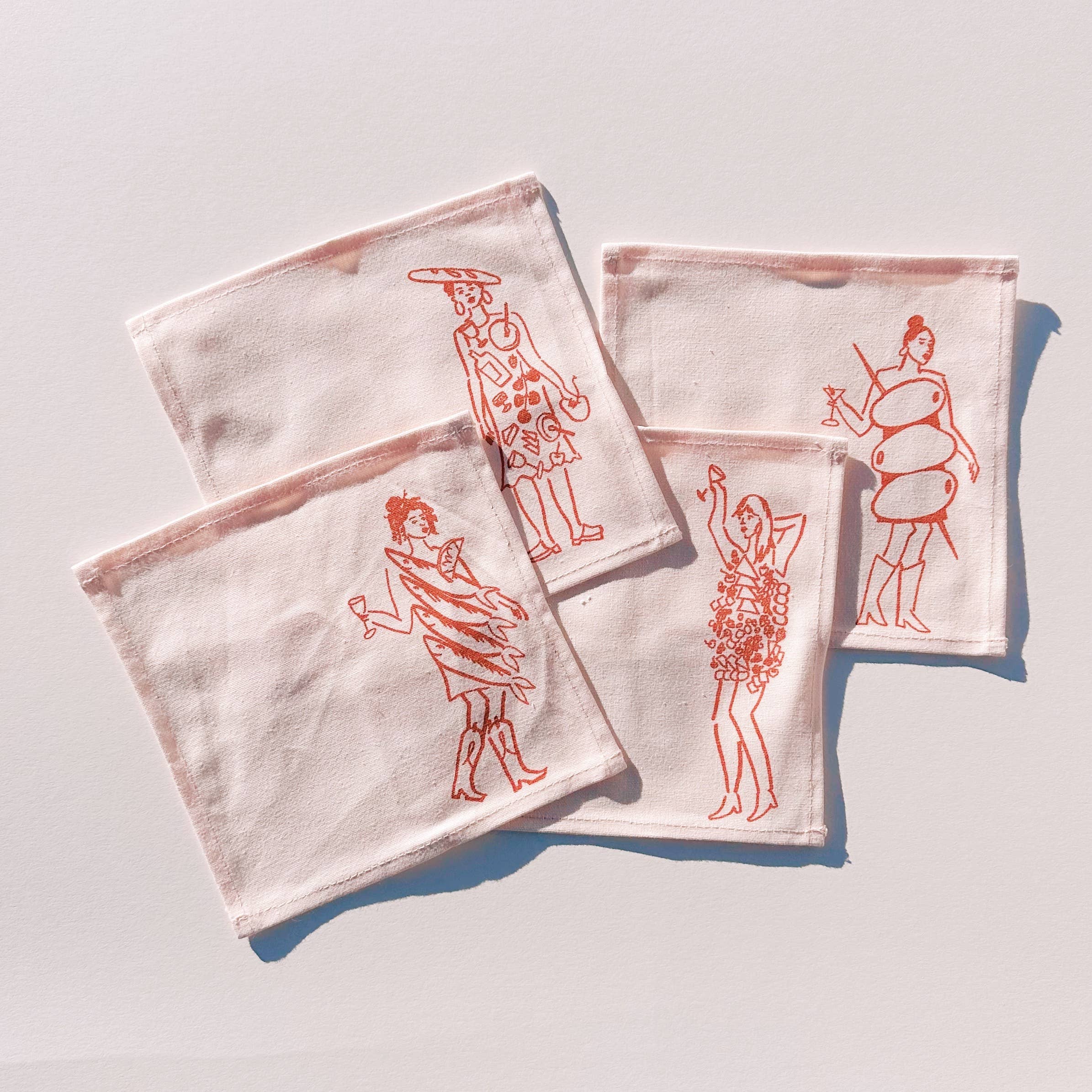 Set of four white cocktail napkins with red illustrations of dinner girls on a light gray background