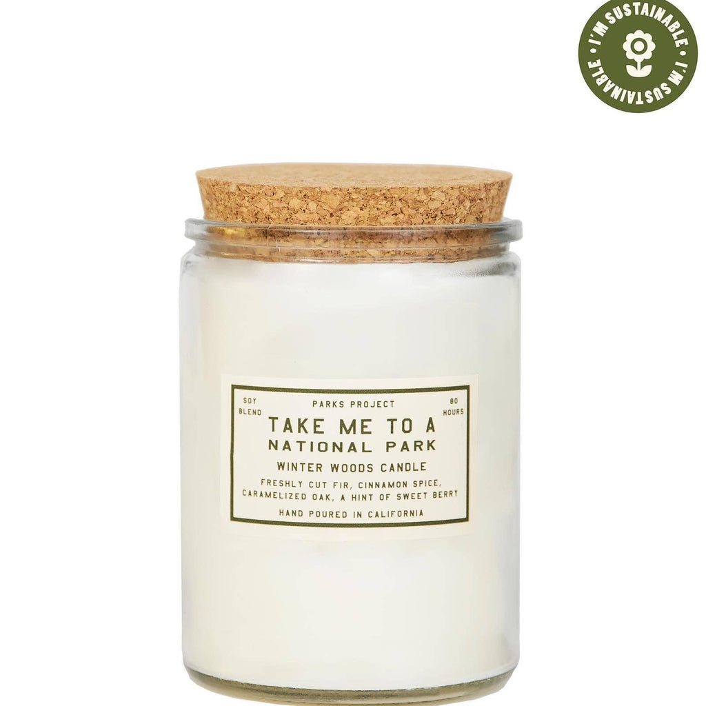 Candle in a glass jar with a cork lid on a white background, featuring a label and a sustainability logo.
