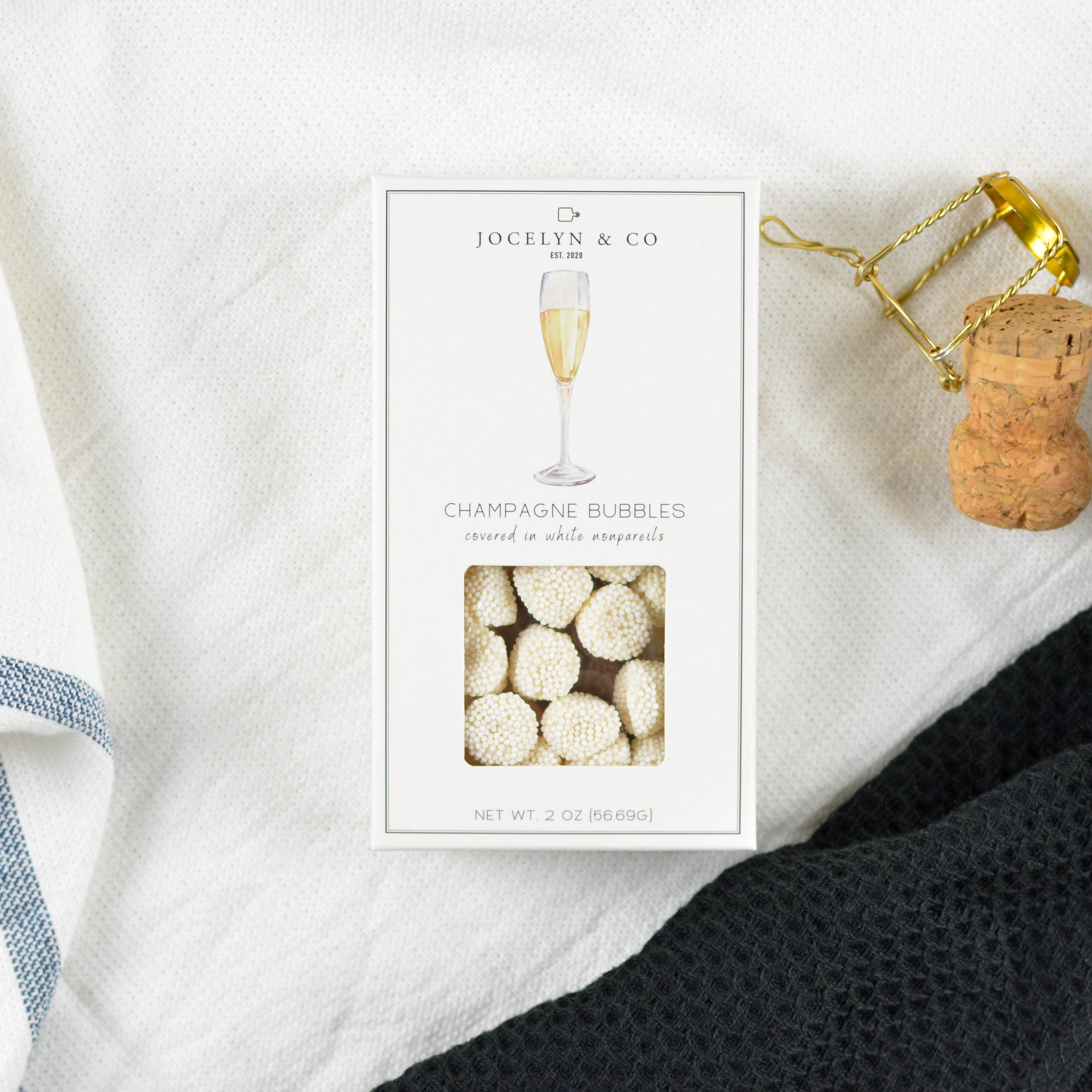 Packaged champagne bubbles with a cork and bottle opener on a white surface