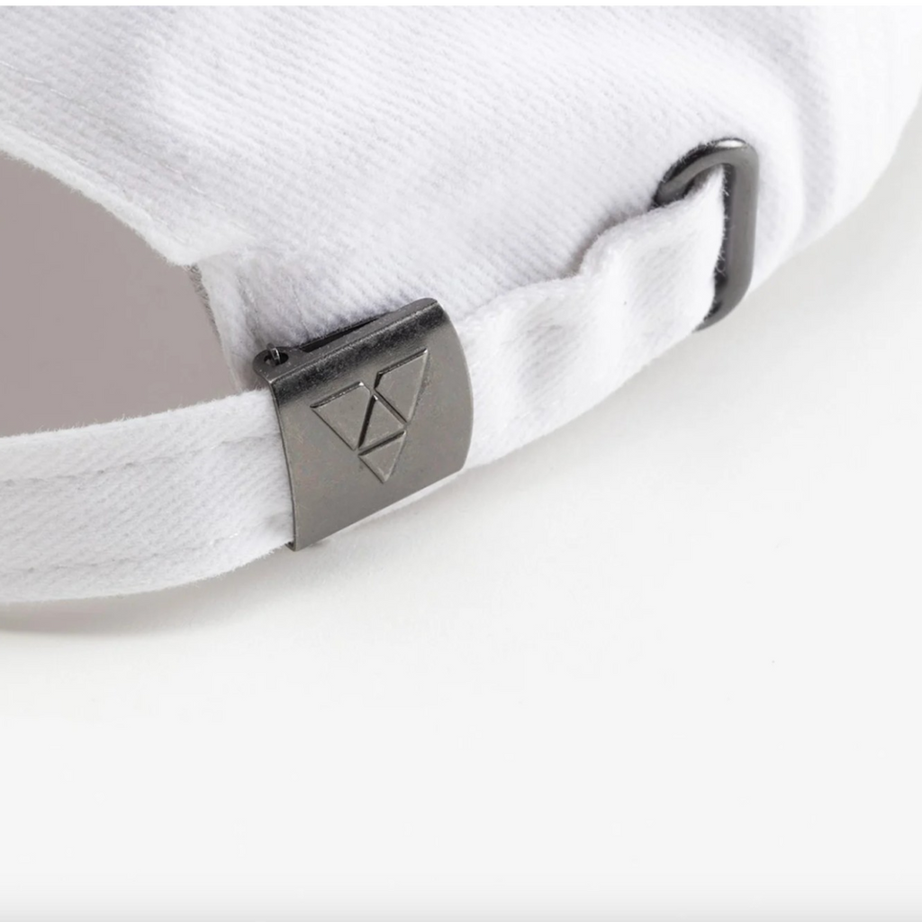 Close-up of a white cap with a metallic logo on a white background