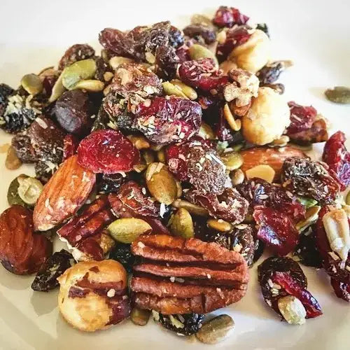 Assorted trail mix with nuts, seeds, and dried fruits on a white plate