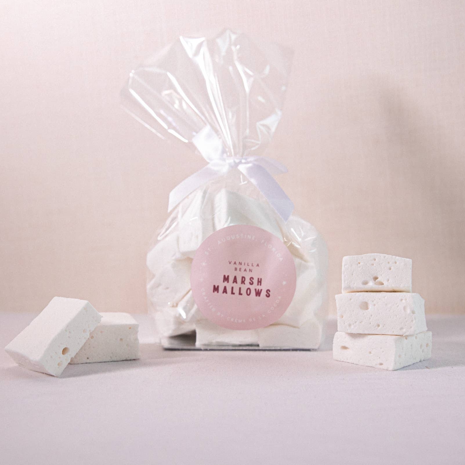 Pink marshmallow in a clear cellophane bag with white packaging on a light pink background