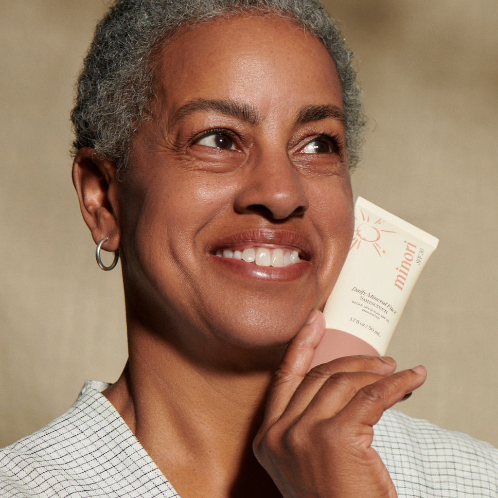 Woman holding a skincare product with a neutral background