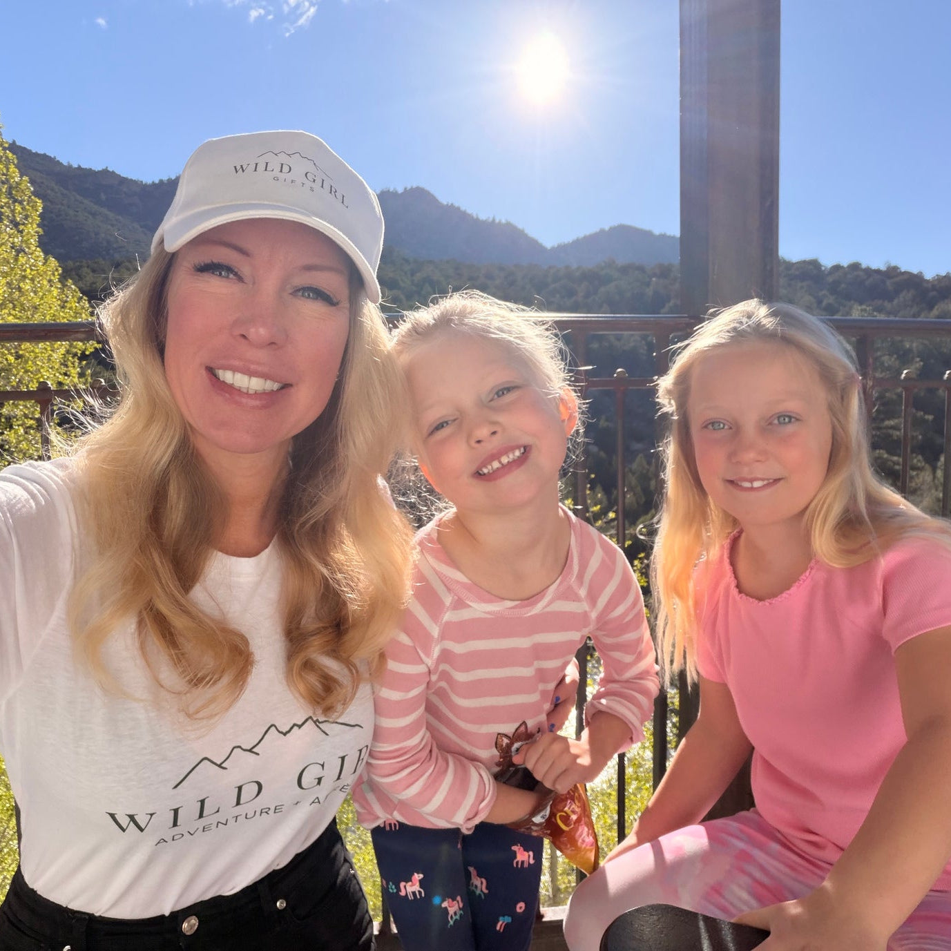 Kim and two daughters posing outdoors with mountains in the background