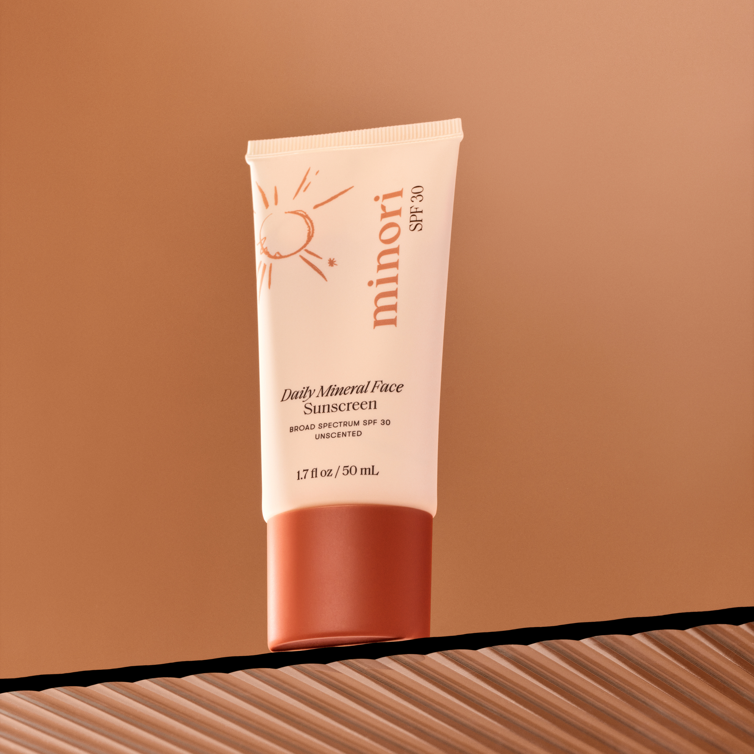 Tube of minori Daily Mineral Face Sunscreen on a brown background