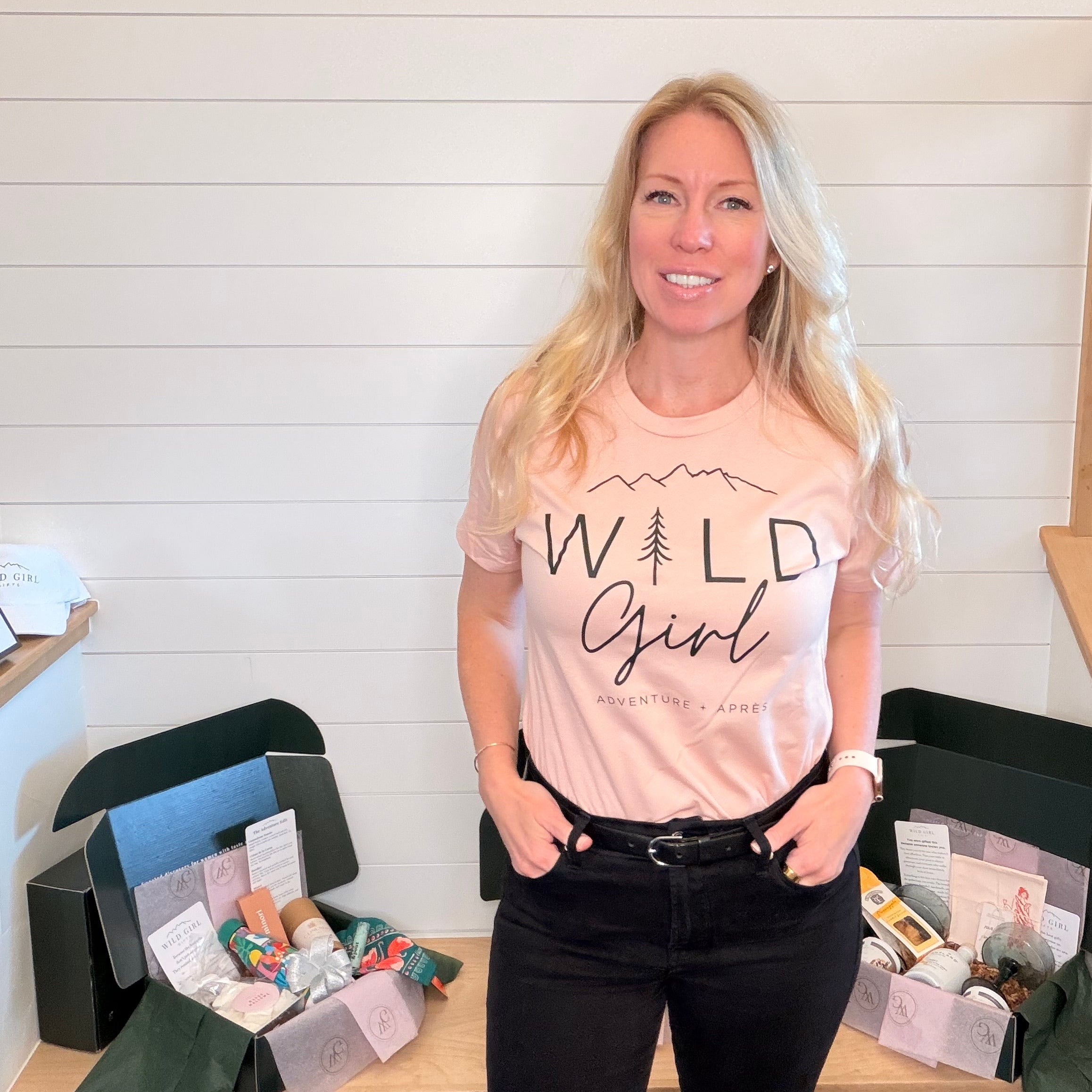 Kim wearing a 'Wild Girl' t-shirt standing in front of a table with boxes.