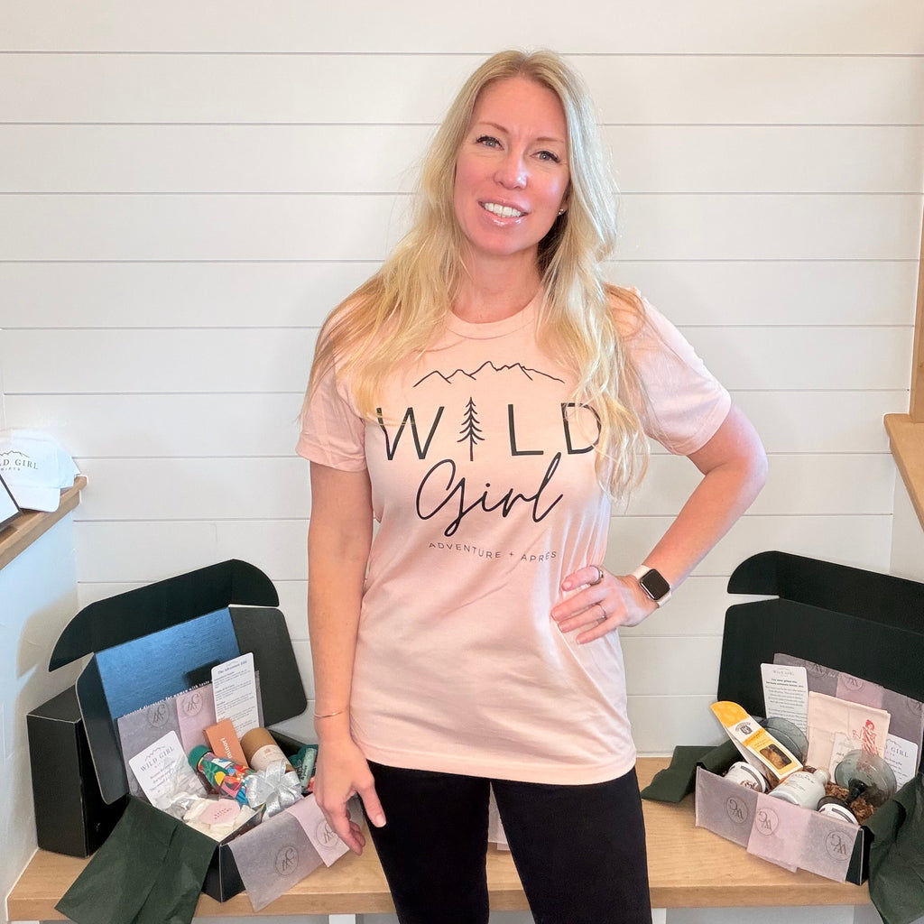 Kim wearing a 'Wild Girl' t-shirt standing in front of a table with boxes.
