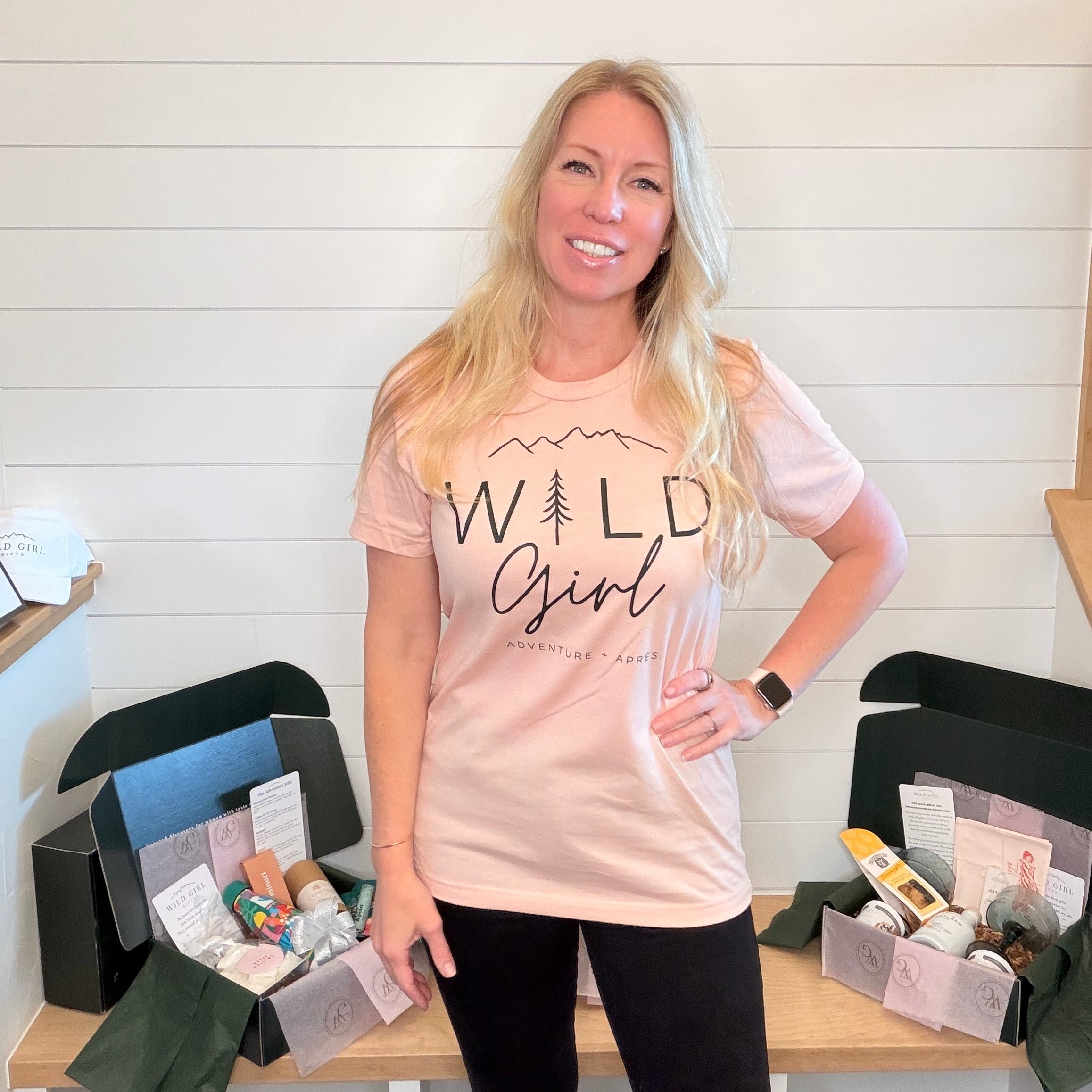 Kim wearing a 'Wild Girl' t-shirt standing in front of a table with boxes.