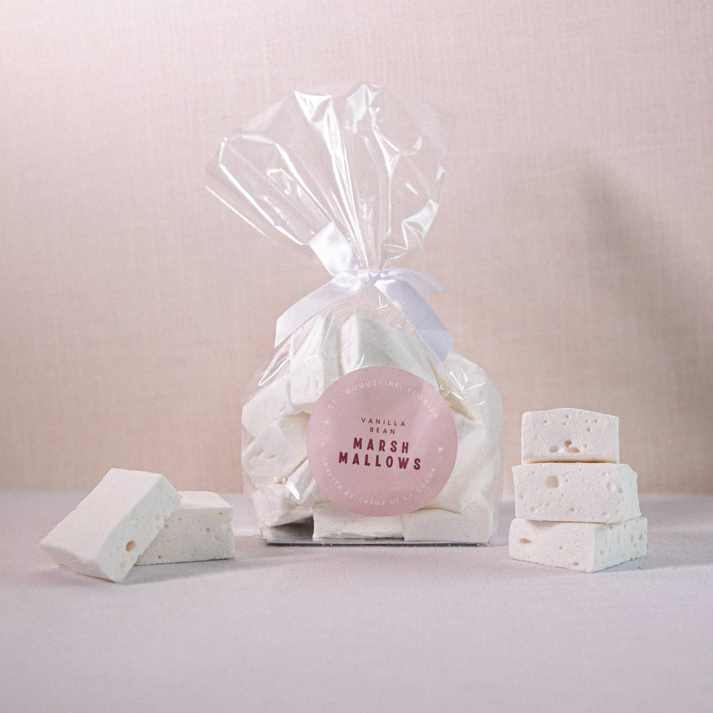 Gourmet handcrafted marshmallows in a clear cellophane bag with white ribbon on a light pink background