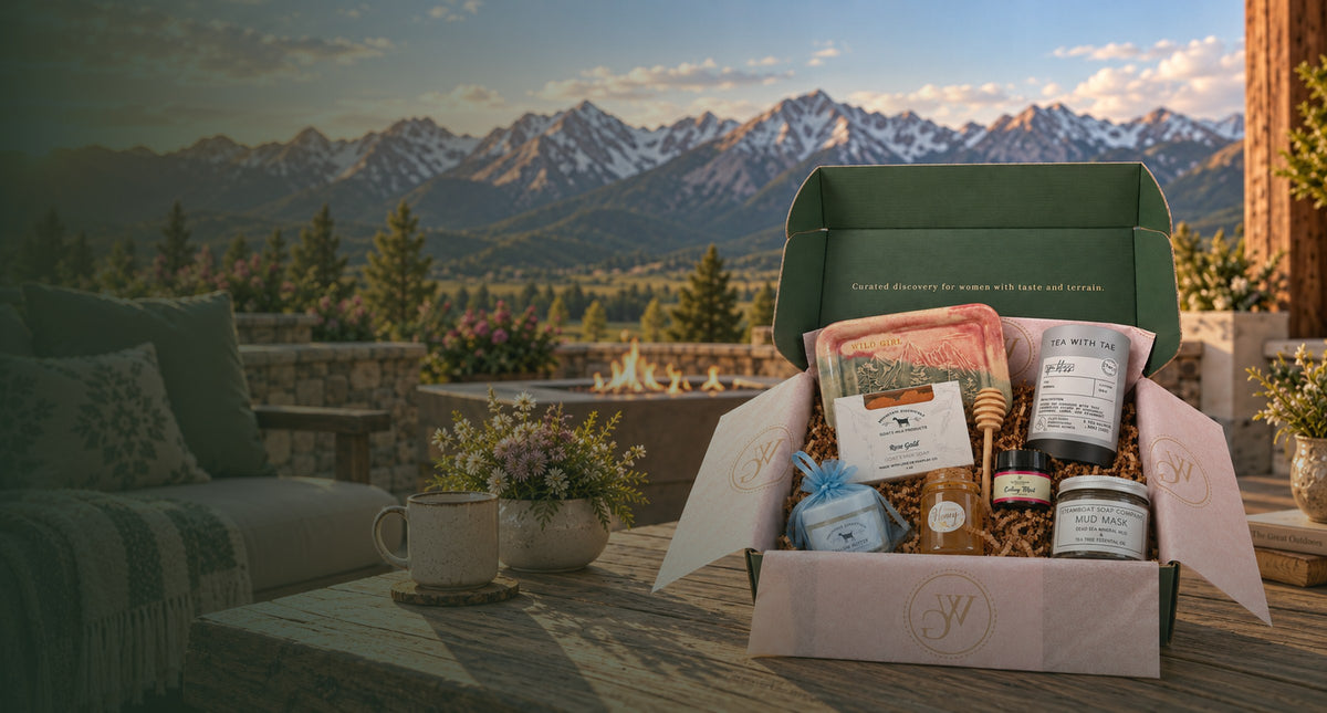 A Wild Girl gift box open on a wooden table in front of the Colorado mountains at sunrise.